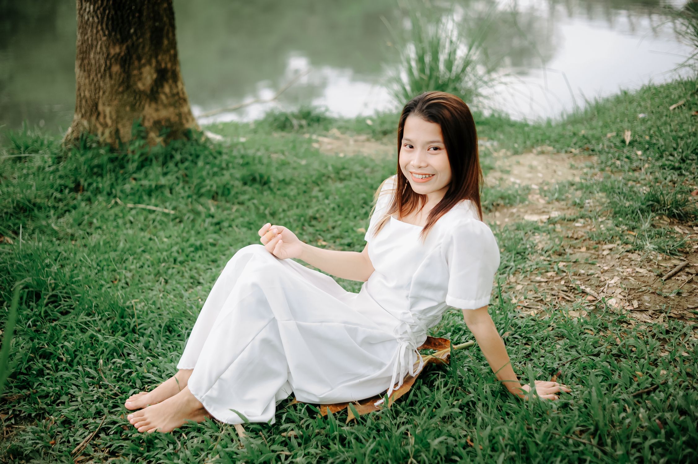 Smiling Woman in White Dress Sitting Outdoors · Free Stock Photo