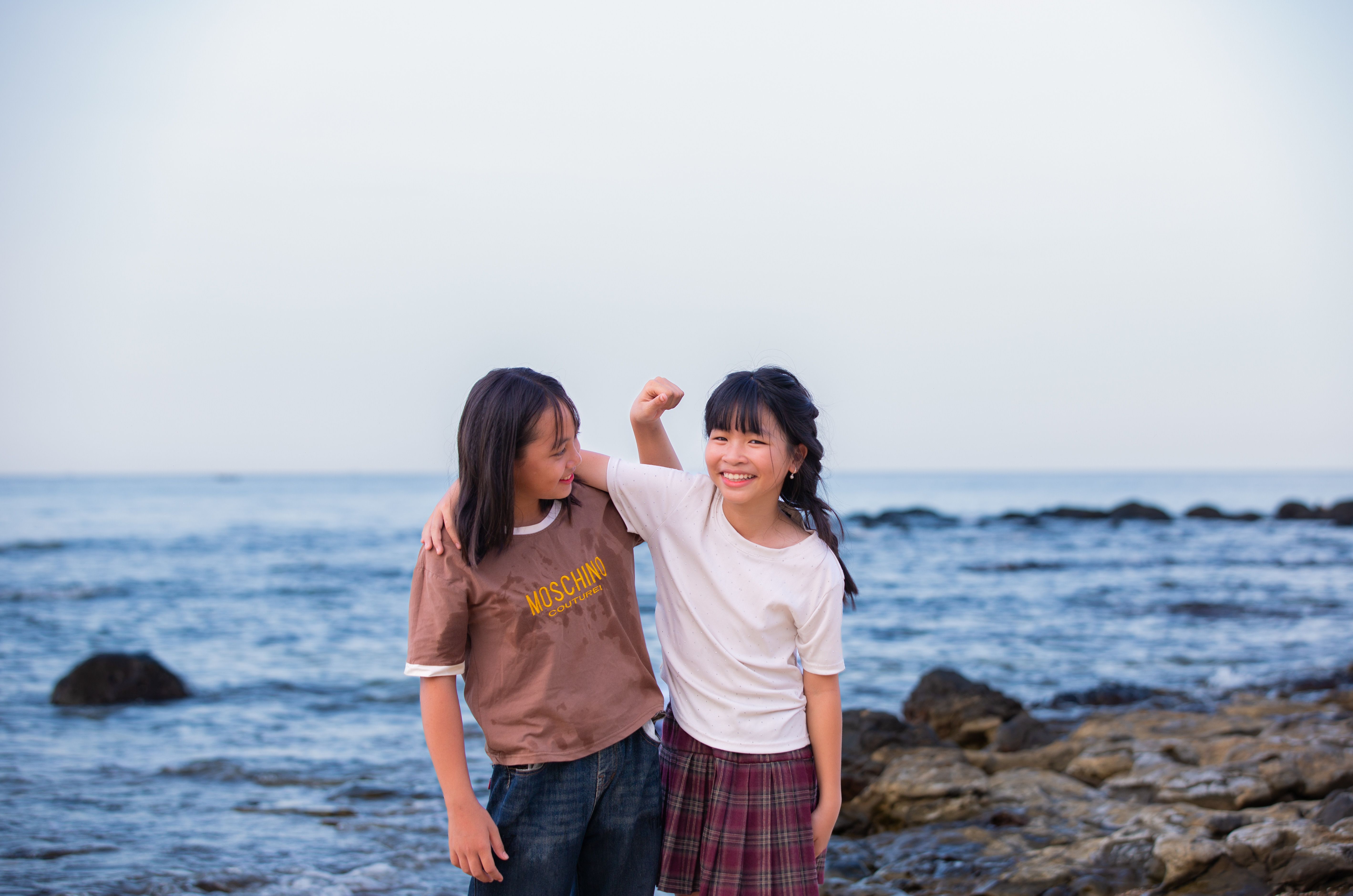 Two smiling teenagers enjoying a fun day by the sea, embracing with a joyful spirit.
