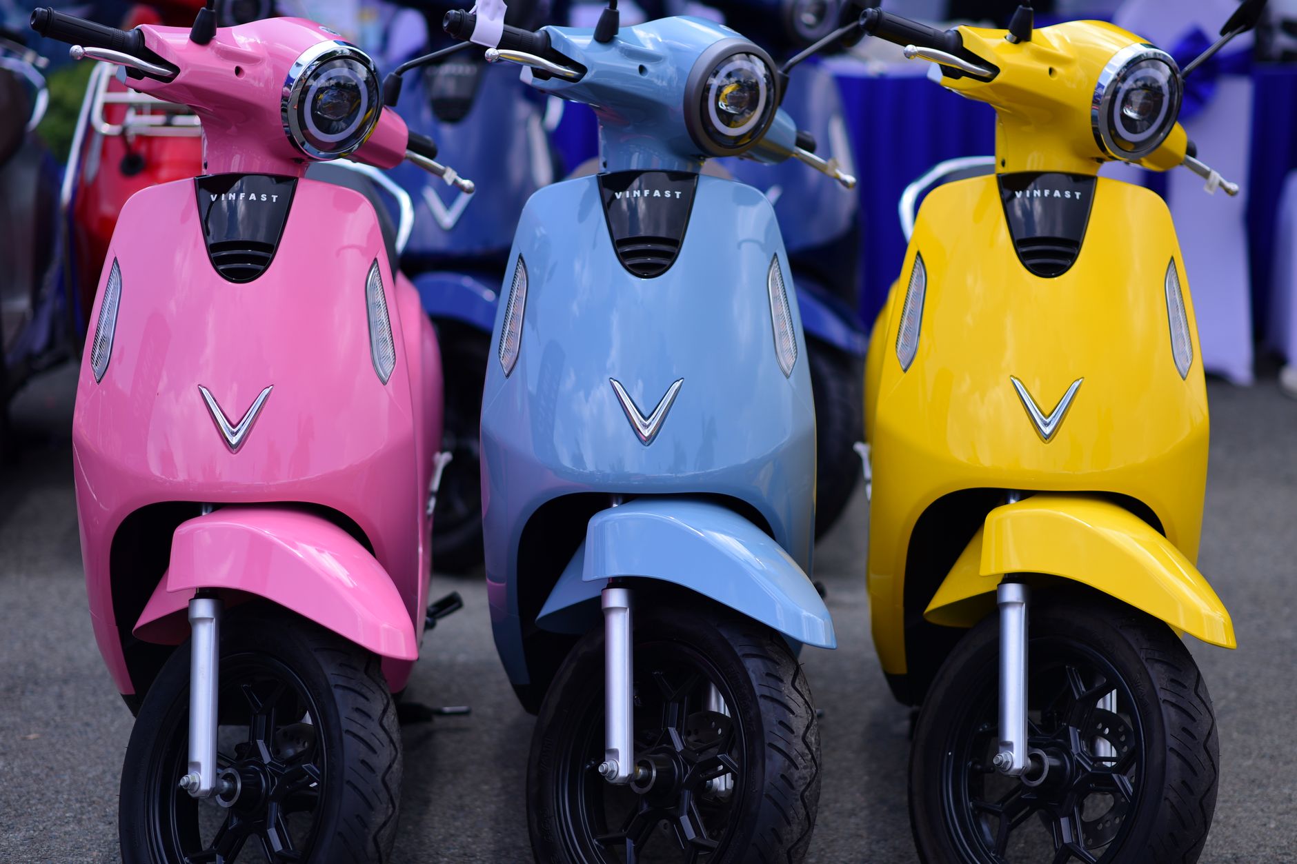 A vibrant outdoor display of pink, blue, and yellow VinFast scooters. Eye-catching and modern.