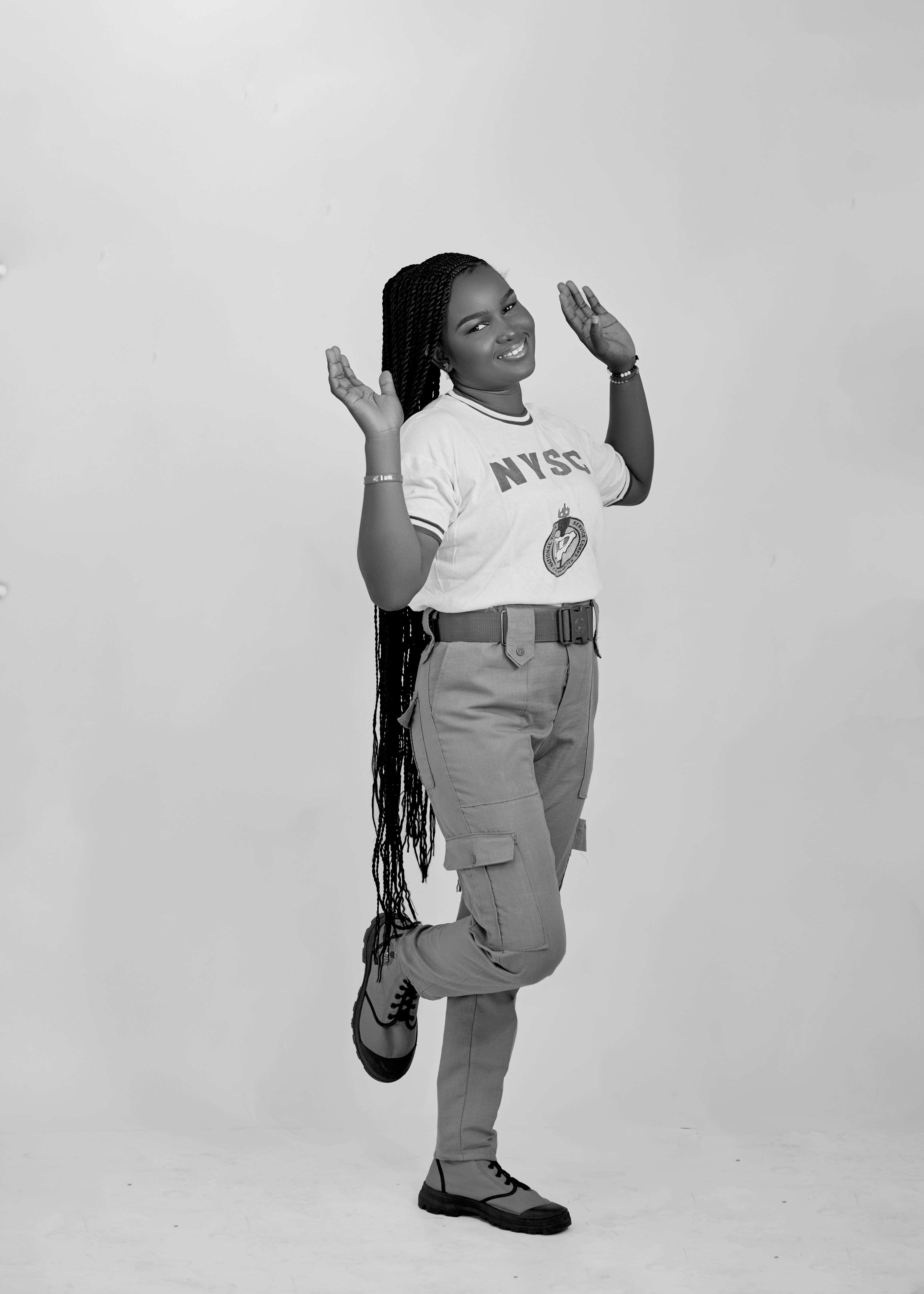 Black and white photo of a woman in uniform playfully posing indoors.