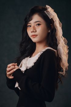 Stunning portrait of a woman wearing a lace veil and formal attire, set against a dark background.