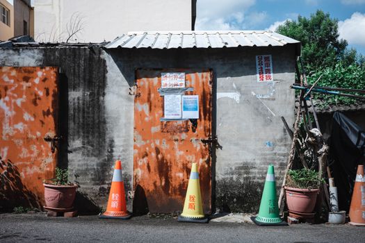 Explore a rustic alley in Taichung, Taiwan, with vibrant traffic cones and worn textures.
