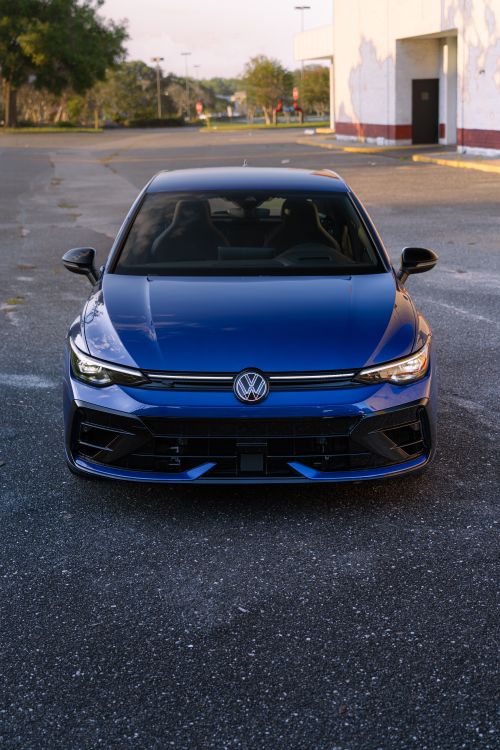 Free Front view of a sleek blue Volkswagen car parked outdoors, showcasing modern automotive design. Stock Photo