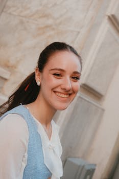 Happy woman with casual attire standing outdoors against a stone background.