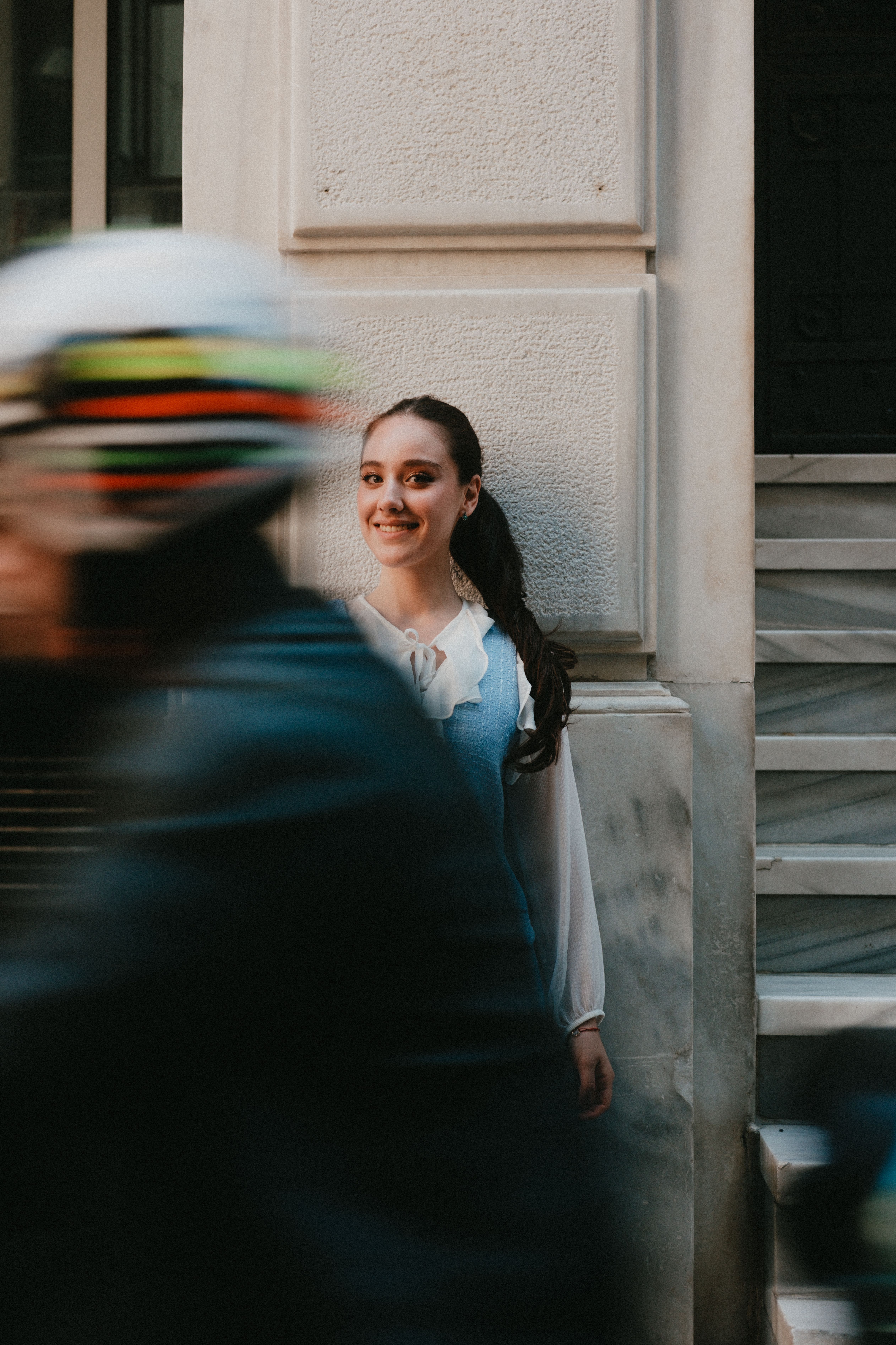 Young woman smiling on urban street with motion blur of a passing motorcyclist.