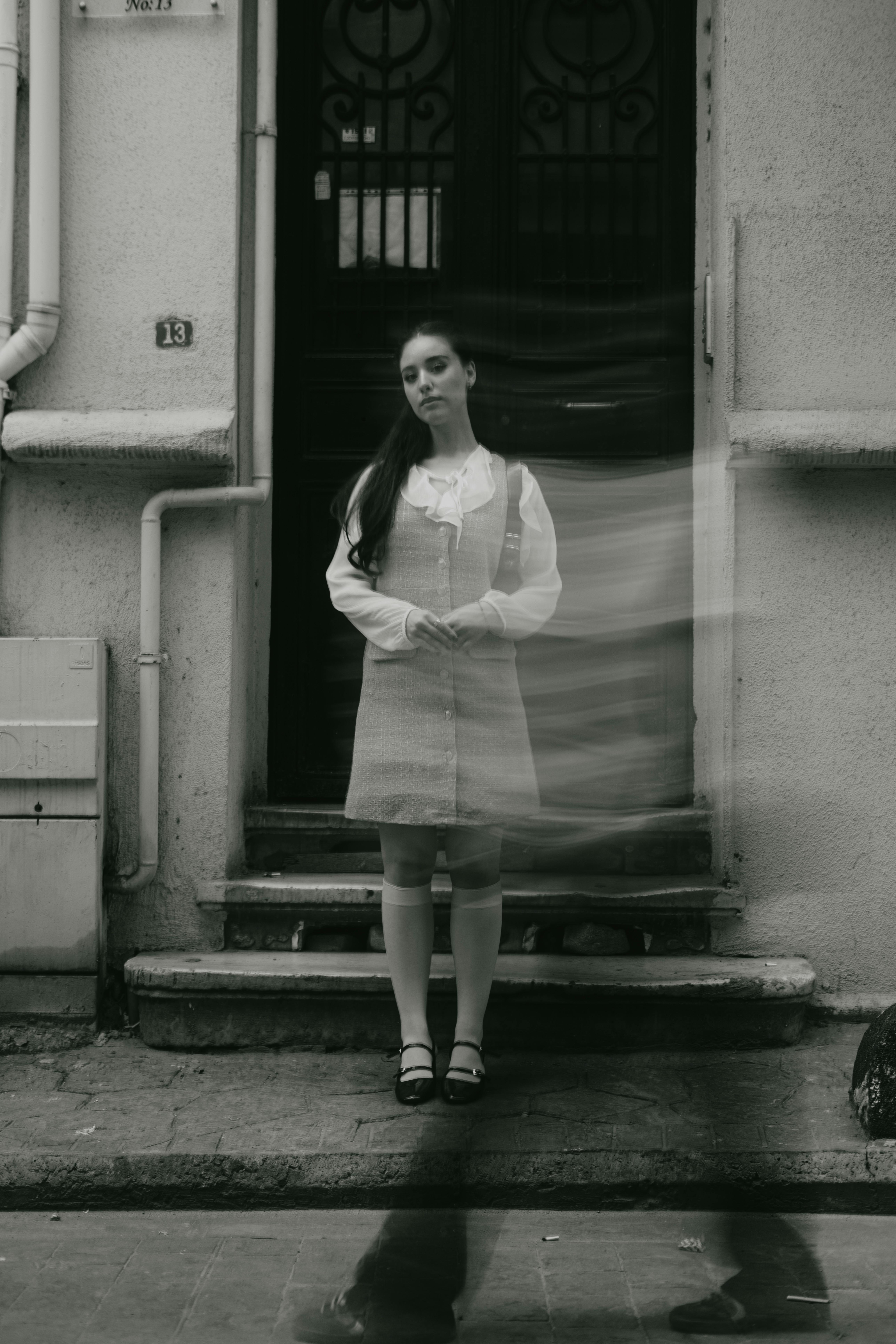 Woman standing in front of a vintage doorway with blurred motion effect, black and white.