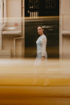 A woman stands on a city street, captured with dynamic motion blur in front of a building.