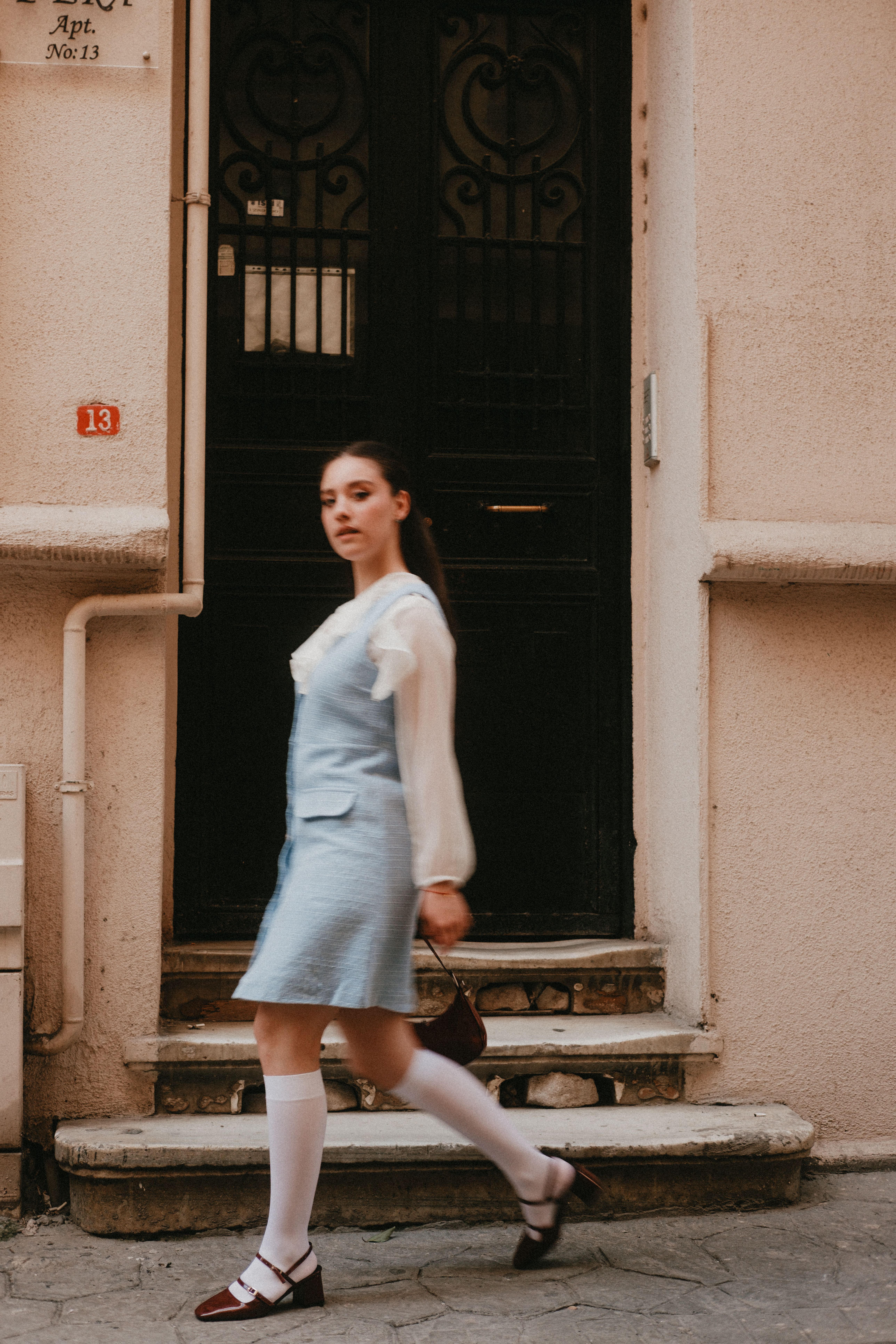 Young Woman Walking Past Vintage Doorway · Free Stock Photo
