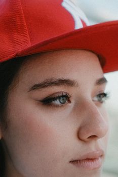 Close-up portrait of a young woman wearing a red cap with soft natural lighting.
