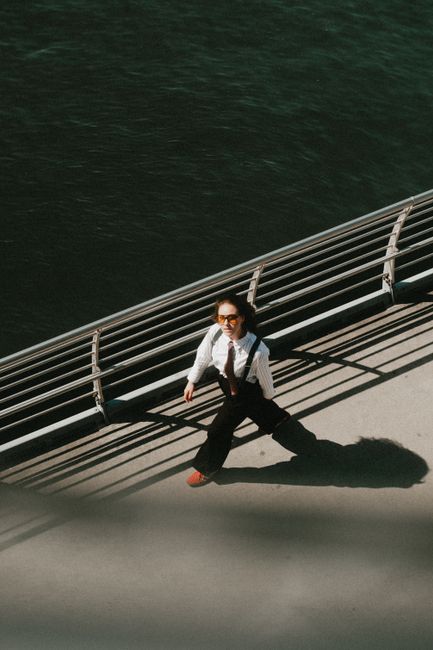 Businesswoman in formal attire walking along a riverside promenade during the day.