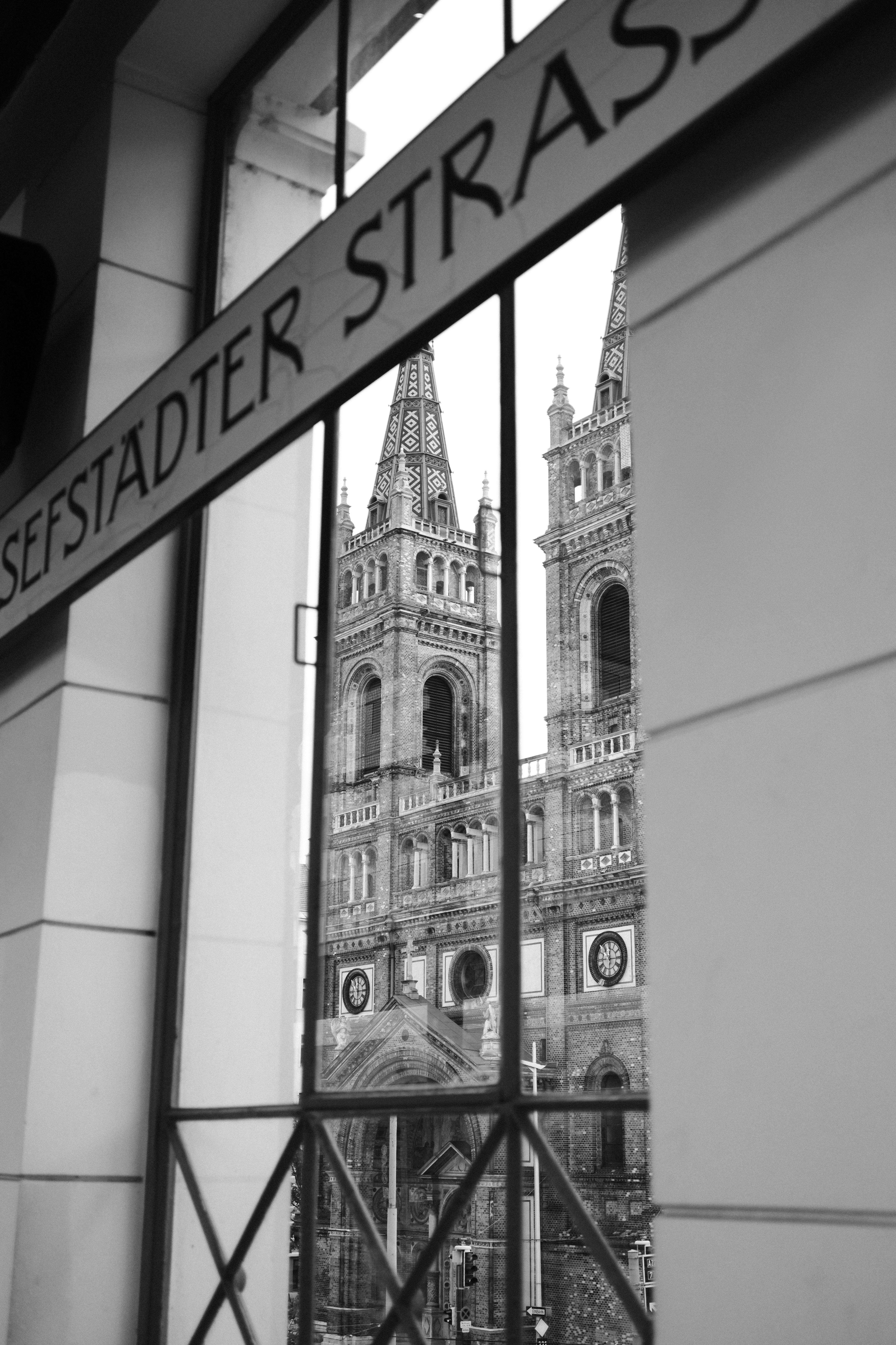 Black and white view of cathedral towers seen through a subway window, offering a gothic architectural glimpse.