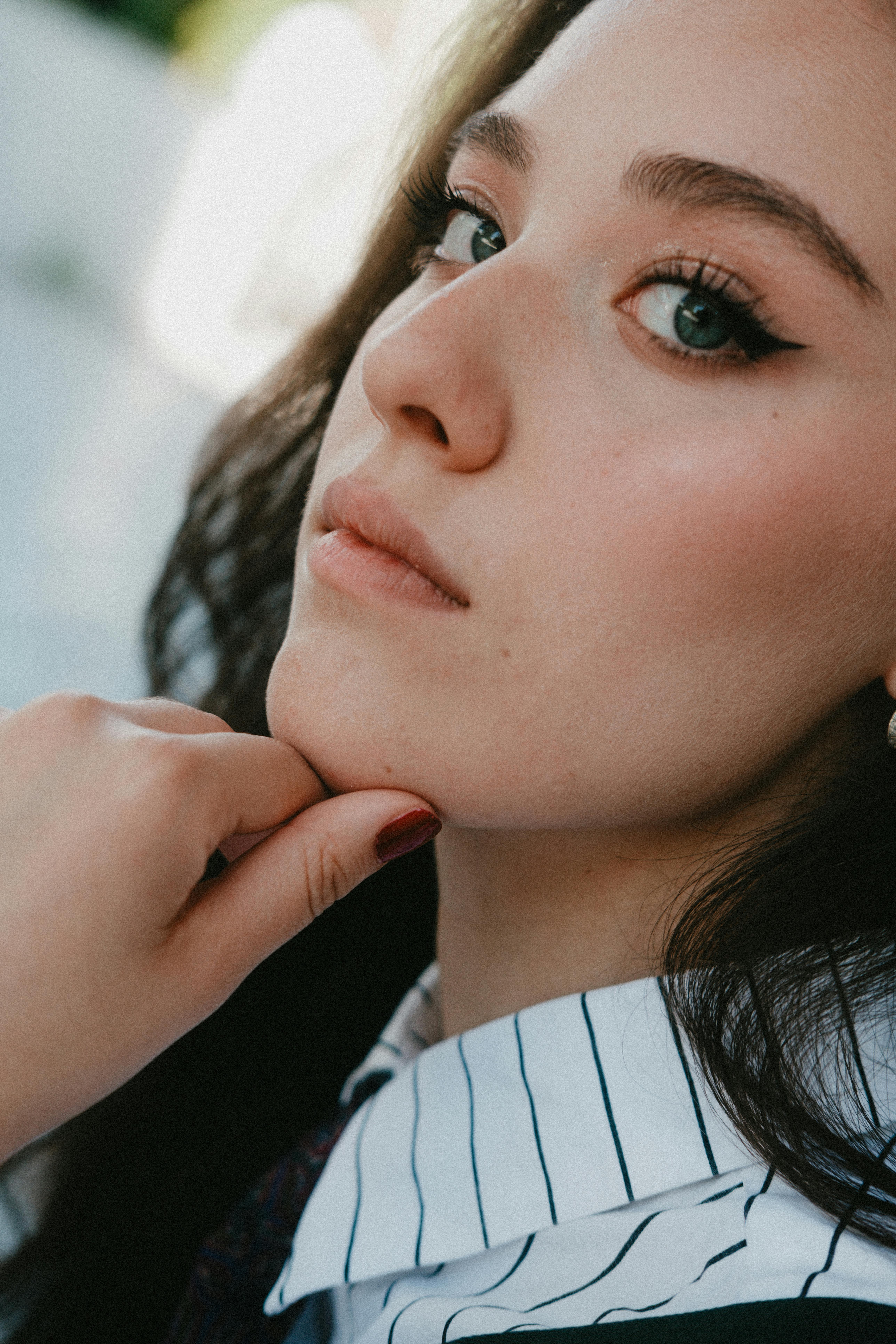 Elegant close-up of a young woman with striking eyes, lost in thought.