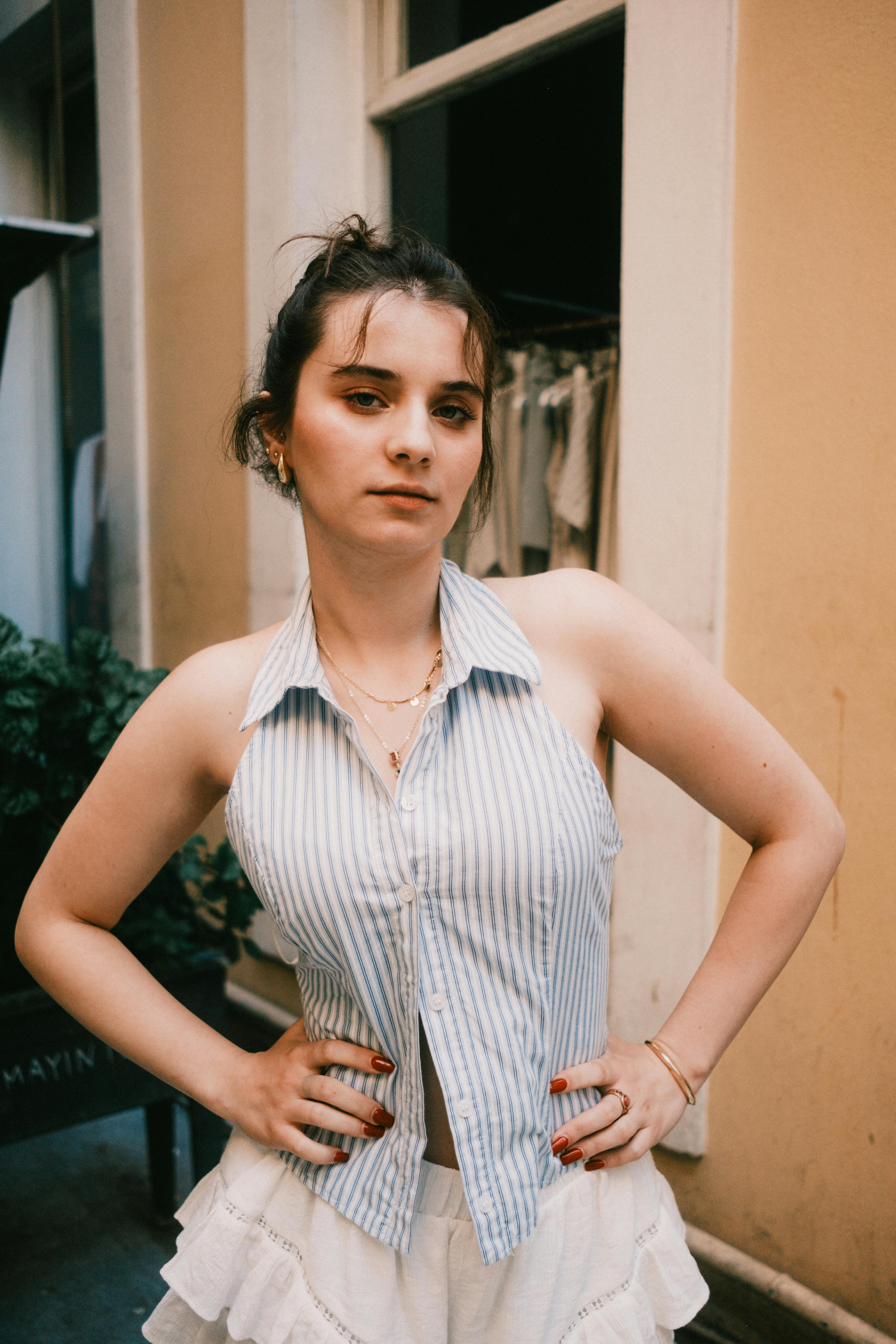 Young woman standing with hands on hips, striped top and skirt, casual style.