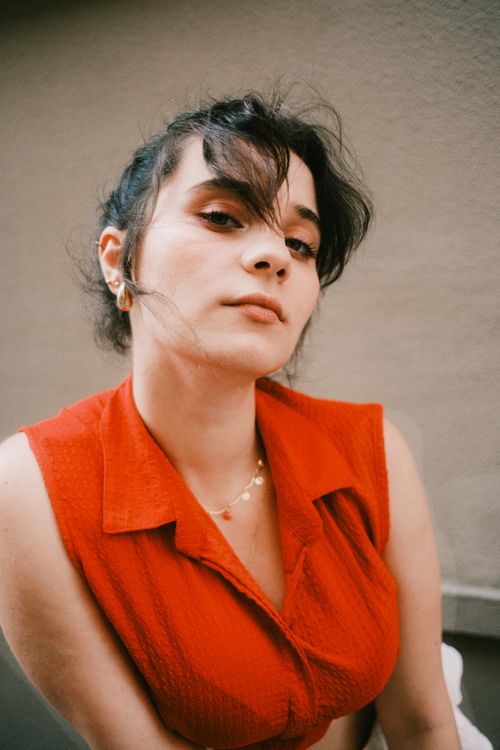 Free Close-up portrait of a woman wearing a red top, looking confident and serene. Stock Photo