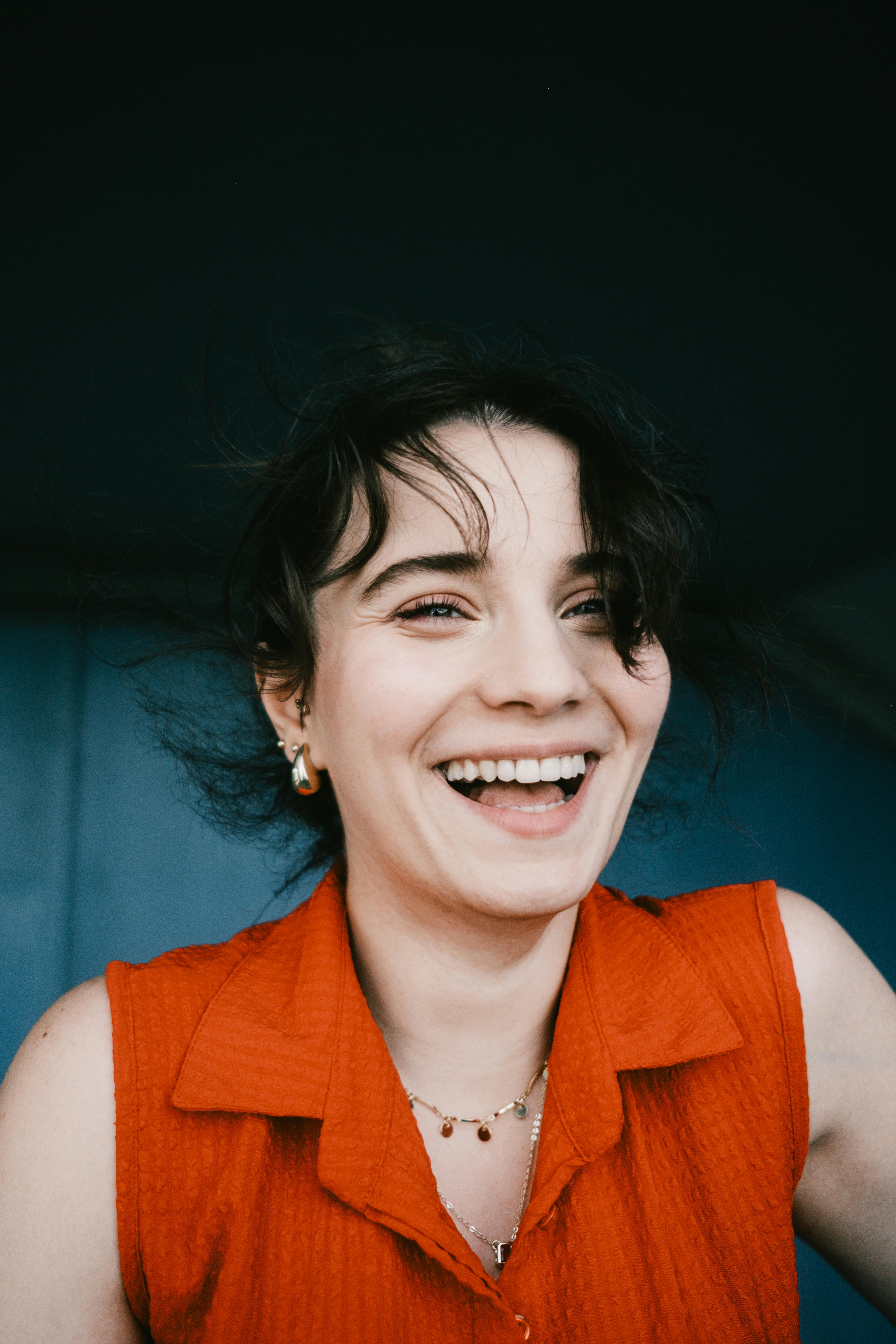 Portrait of a joyful woman laughing, wearing a red shirt.