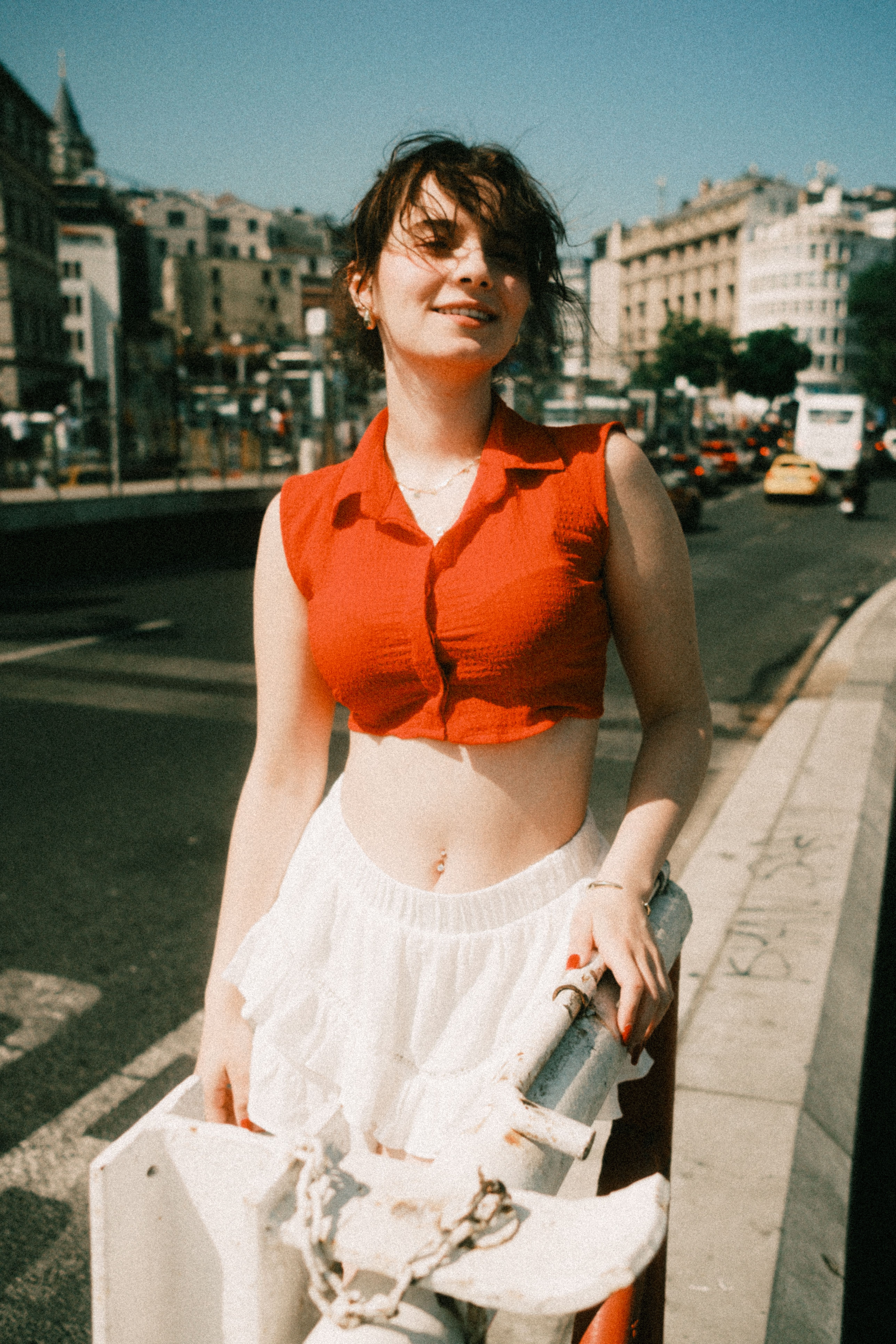 Young woman in red top enjoying summer day in urban landscape.