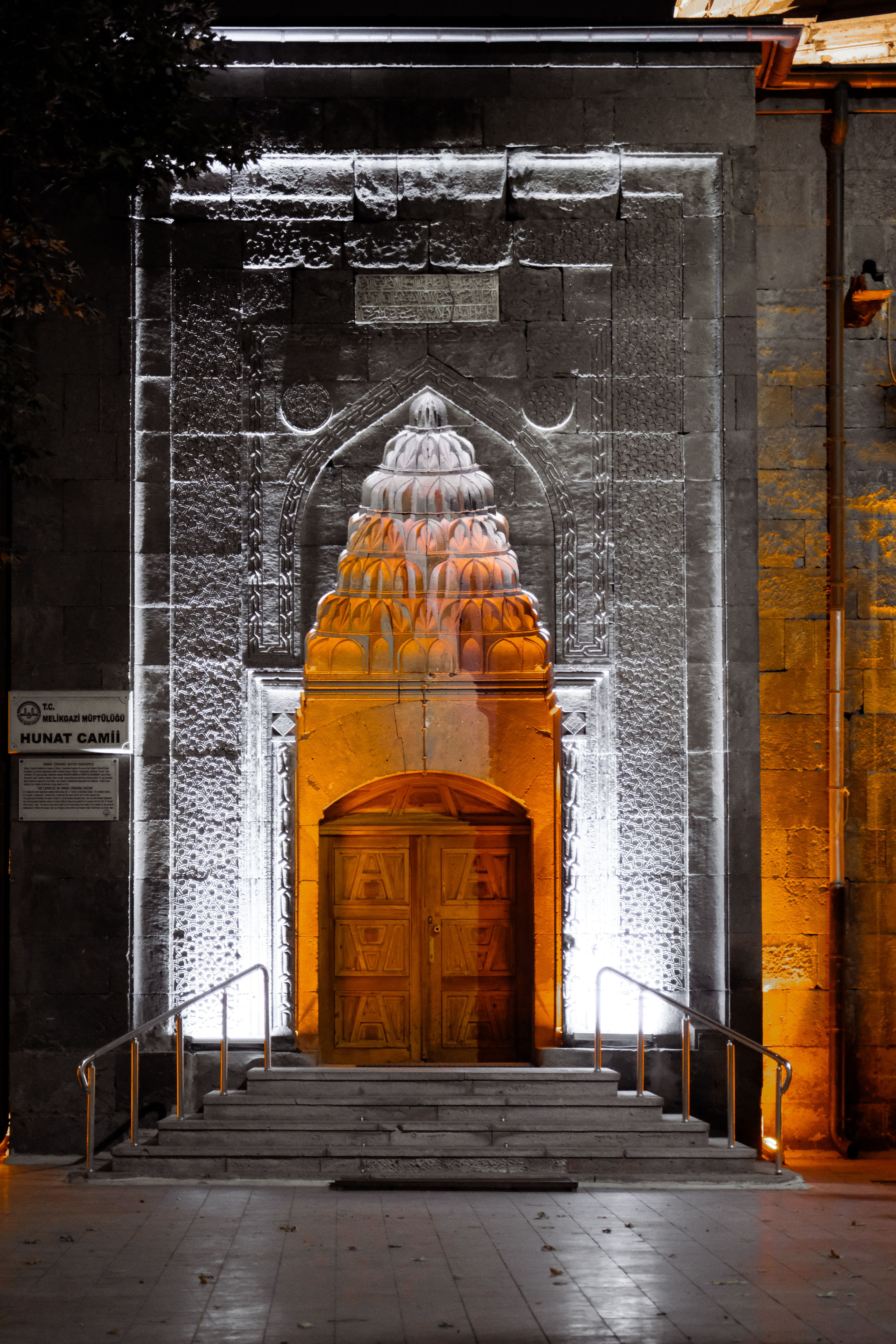 Beautifully lit entrance of the historic Hunat Camii showcasing intricate stonework at night.