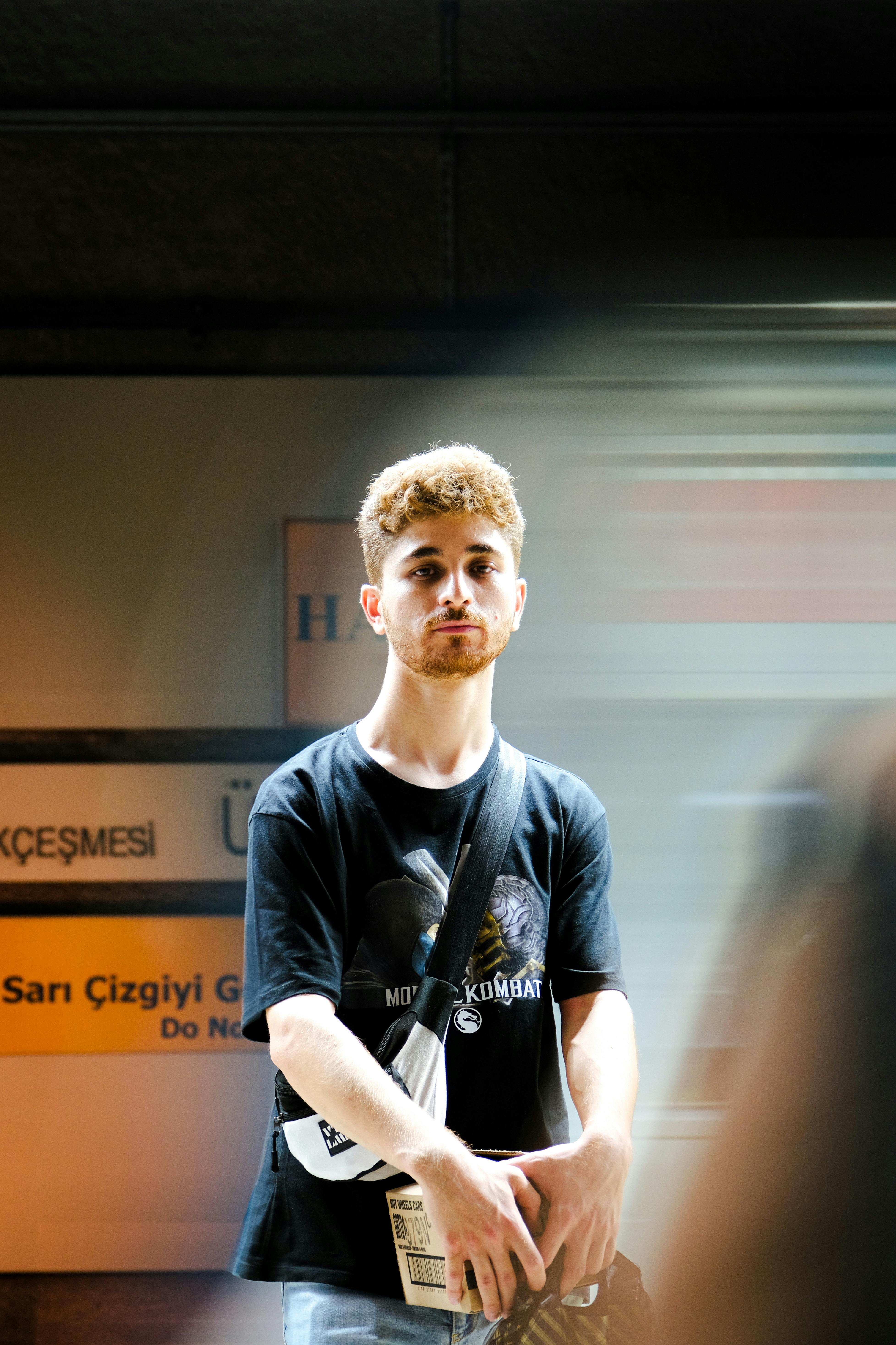 Portrait of a young man standing in a subway with background motion blur.