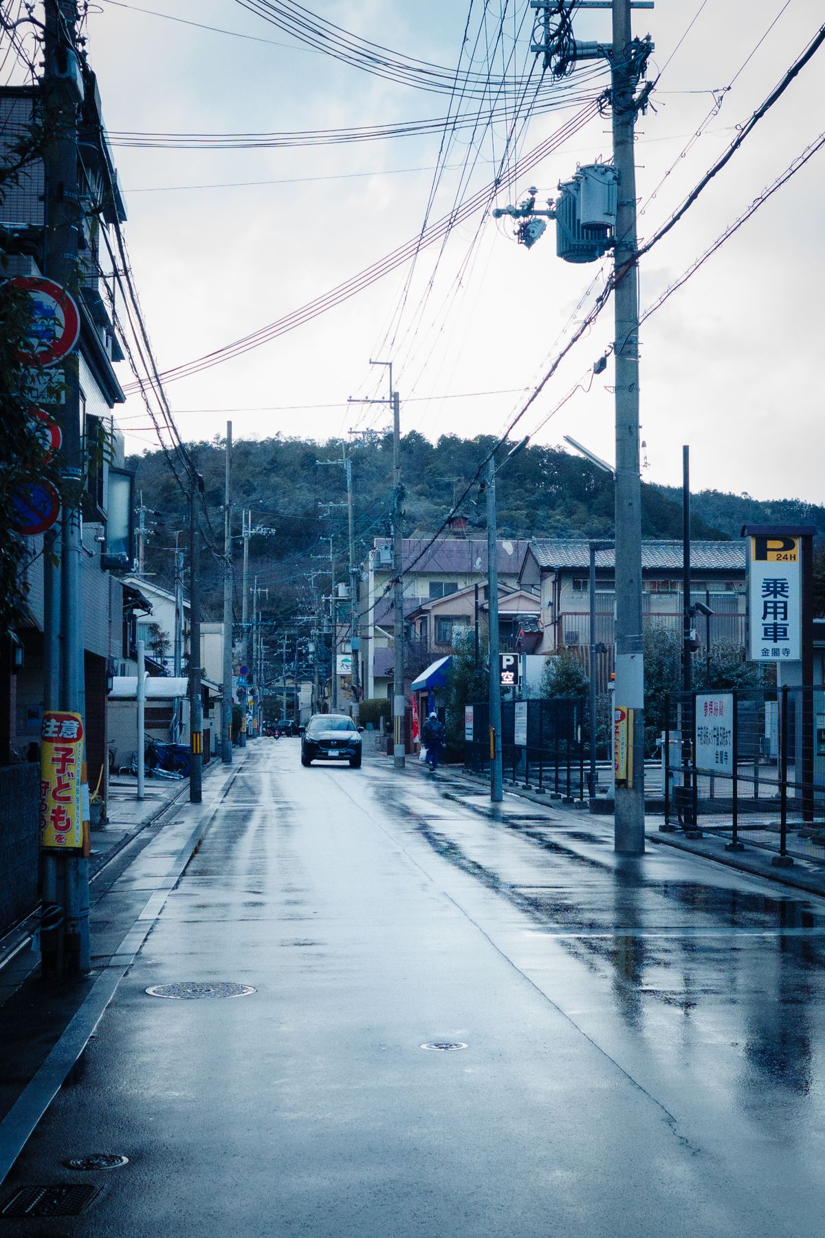 雨に濡れた道路と山あいの町並み