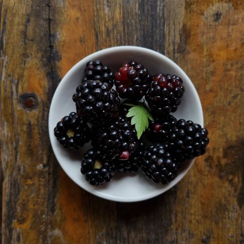 Free A bowl of fresh blackberries on a rustic wooden table, captured in Rize, Türkiye. Stock Photo