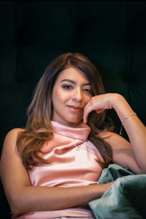 Free Portrait of a woman in a pink satin dress sitting elegantly, exuding confidence. Stock Photo