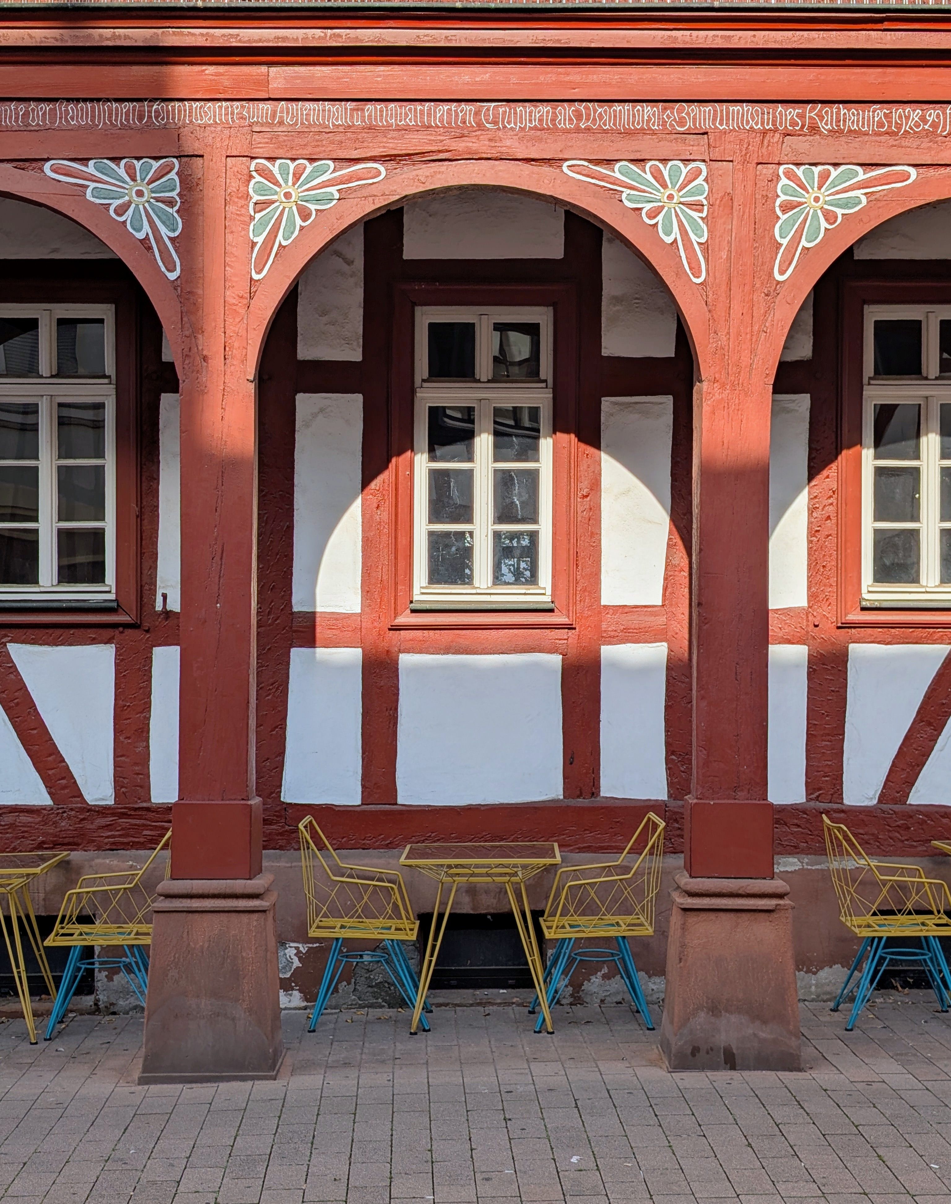 Colorful chairs against a historic timber framed building facade in Groß-Gerau, Germany.