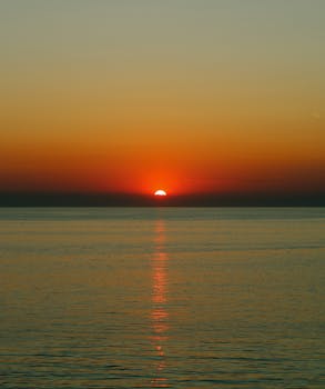 Breathtaking sunset view over calm ocean waters with vivid orange sky reflections.