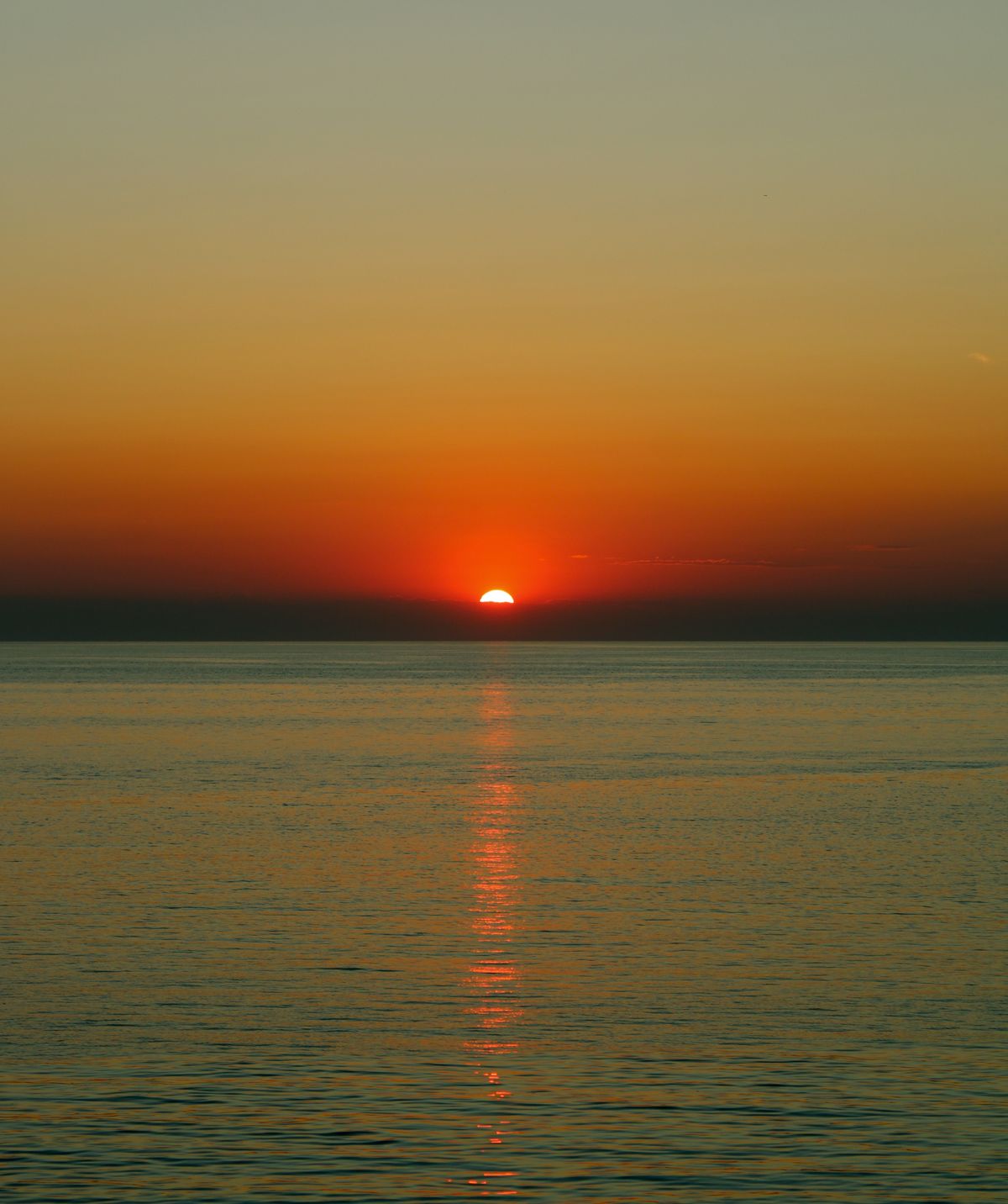 El sol al ponerse sobre el mar con reflejos anaranjados