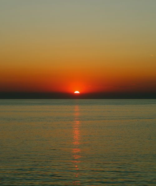 Free Breathtaking sunset view over calm ocean waters with vivid orange sky reflections. Stock Photo