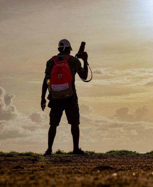 Free Silhouette of a traveler with a camera against a dramatic sunset, capturing the scenic view. Stock Photo