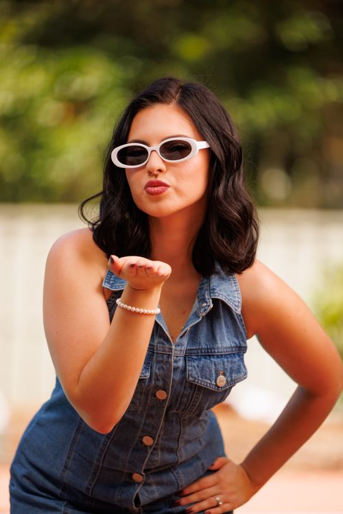 Free Chic young woman in denim and sunglasses blowing a kiss outside in Sanford, Florida. Stock Photo