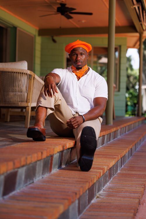Free Casual portrait of a man in a vibrant outfit relaxing on porch steps in Sanford, Florida. Stock Photo