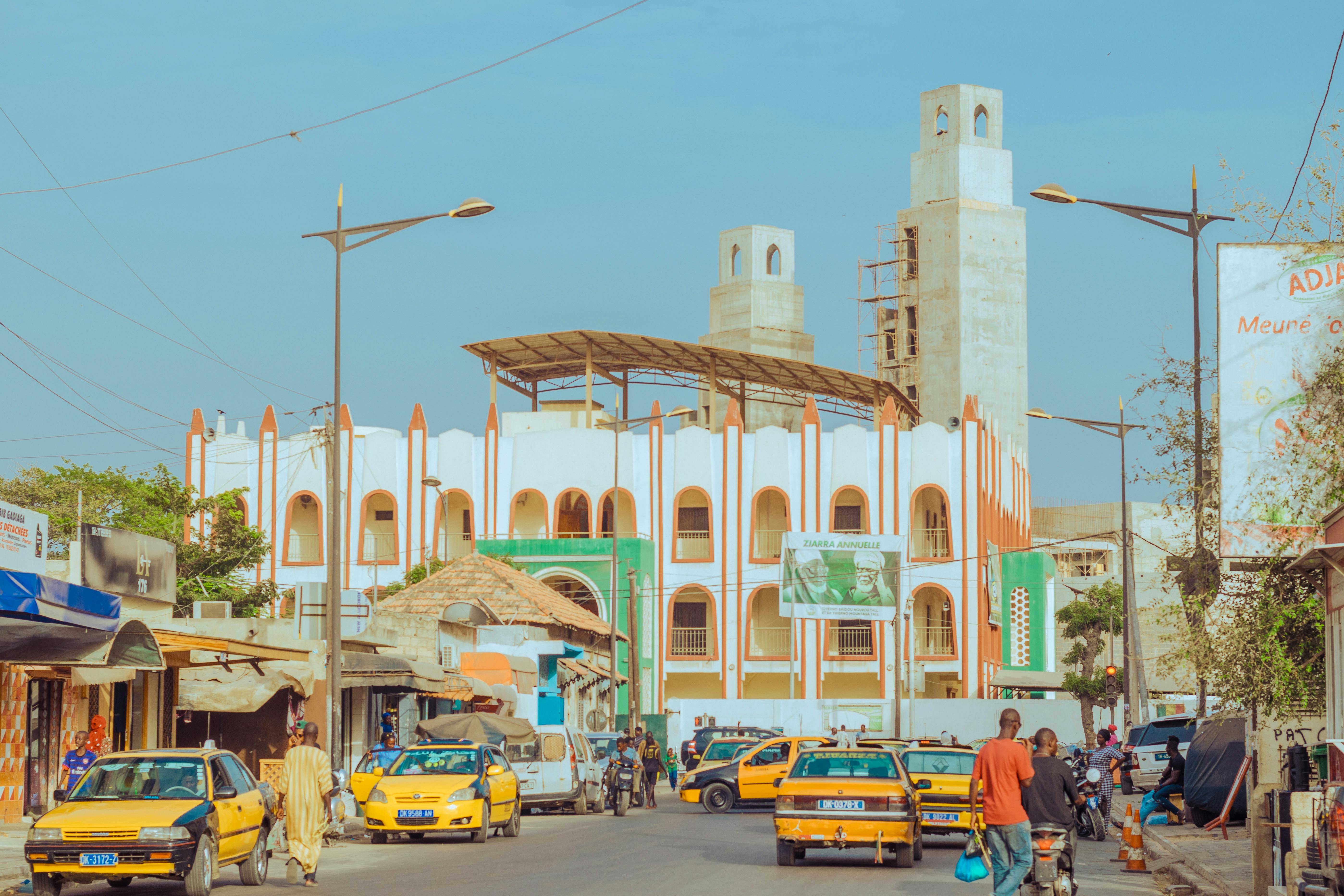 A vibrant street scene featuring an Islamic mosque with distinct architecture under a clear blue sky.