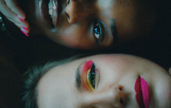 Intimate portrait of two women with colorful makeup, showcasing diversity and beauty.