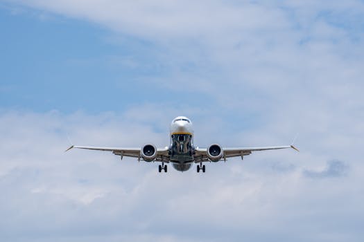 Airplane descending against a blue sky at Manises Airport in Spain, showcasing modern civil aviation.