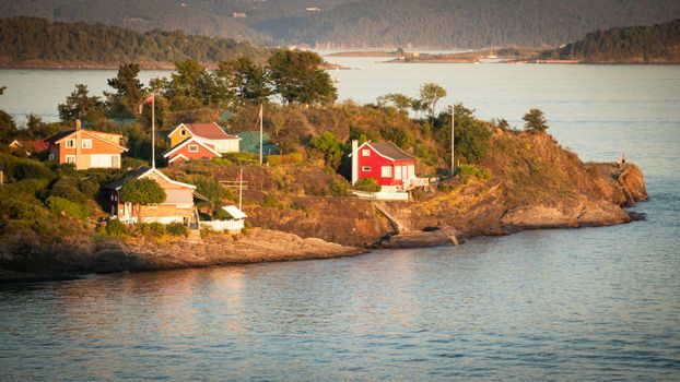 Charming houses on a rocky coastal cliff in Vestland, Norway during golden hour.