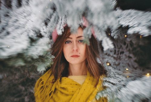 Free A woman stands amidst snowy branches, wrapped in a warm yellow scarf. Stock Photo