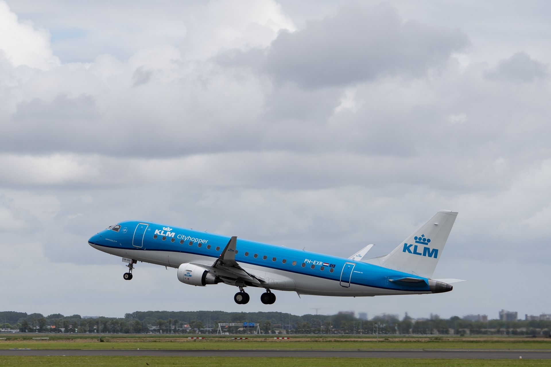 KLM Cityhopper Embraer jet aircraft takes off under a cloudy sky, showcasing aviation in action.