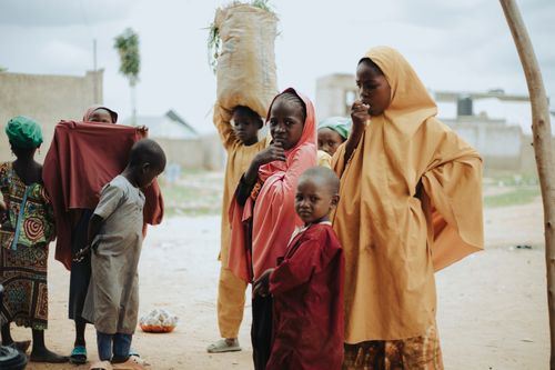 Free Children in colorful traditional attire gathering outdoors on a cloudy day. Stock Photo