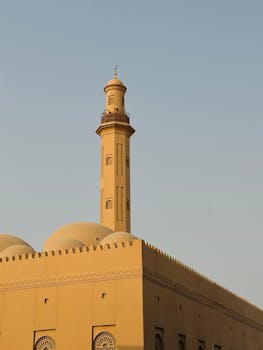A beautifully designed mosque minaret captured against a clear blue sky, highlighting Islamic architecture.