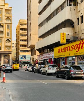 Vibrant city street with shops, traffic, and tall buildings on a sunny day.