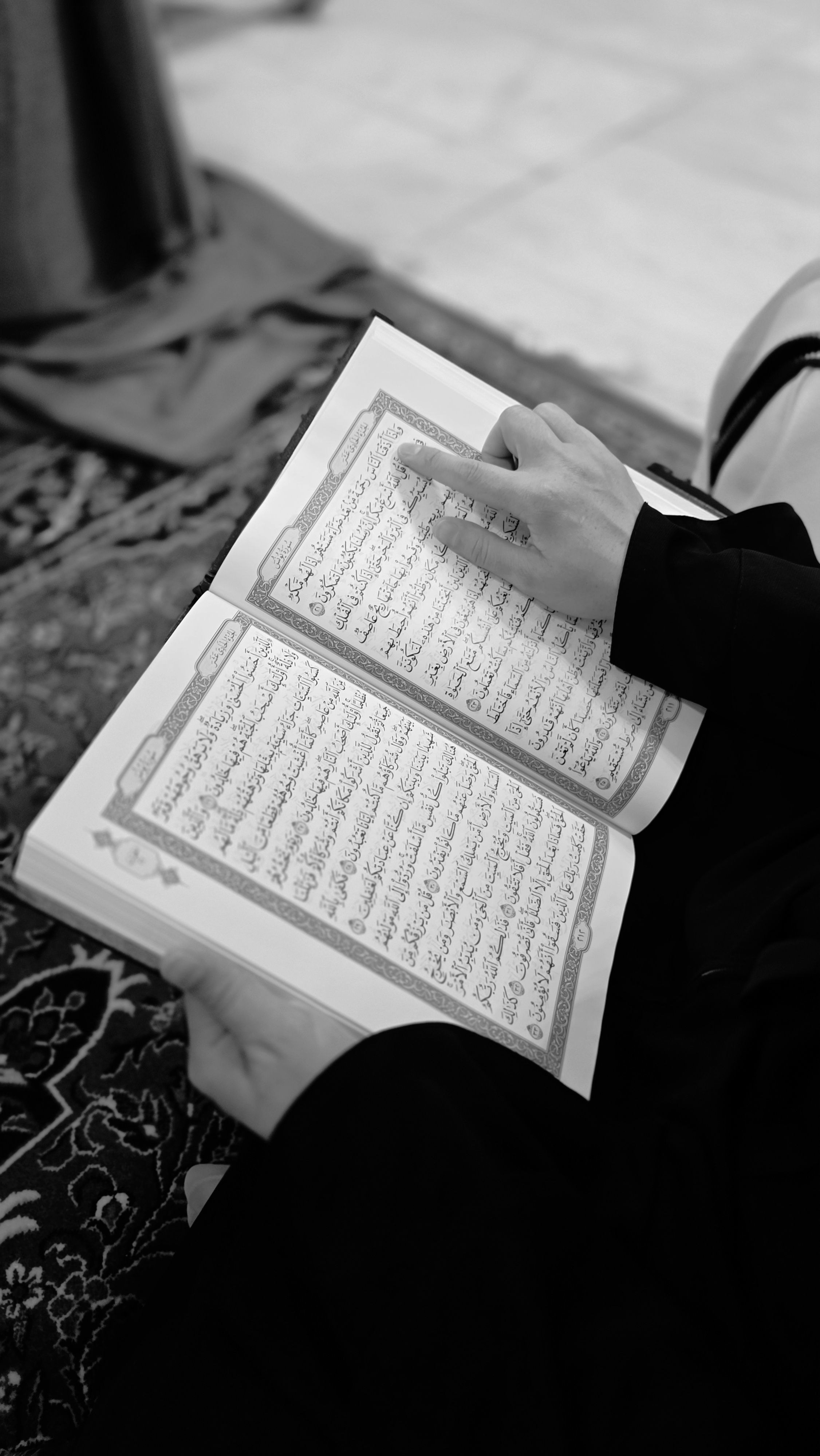 Monochrome image of a person reading a religious text indoors, symbolizing spirituality and peace.