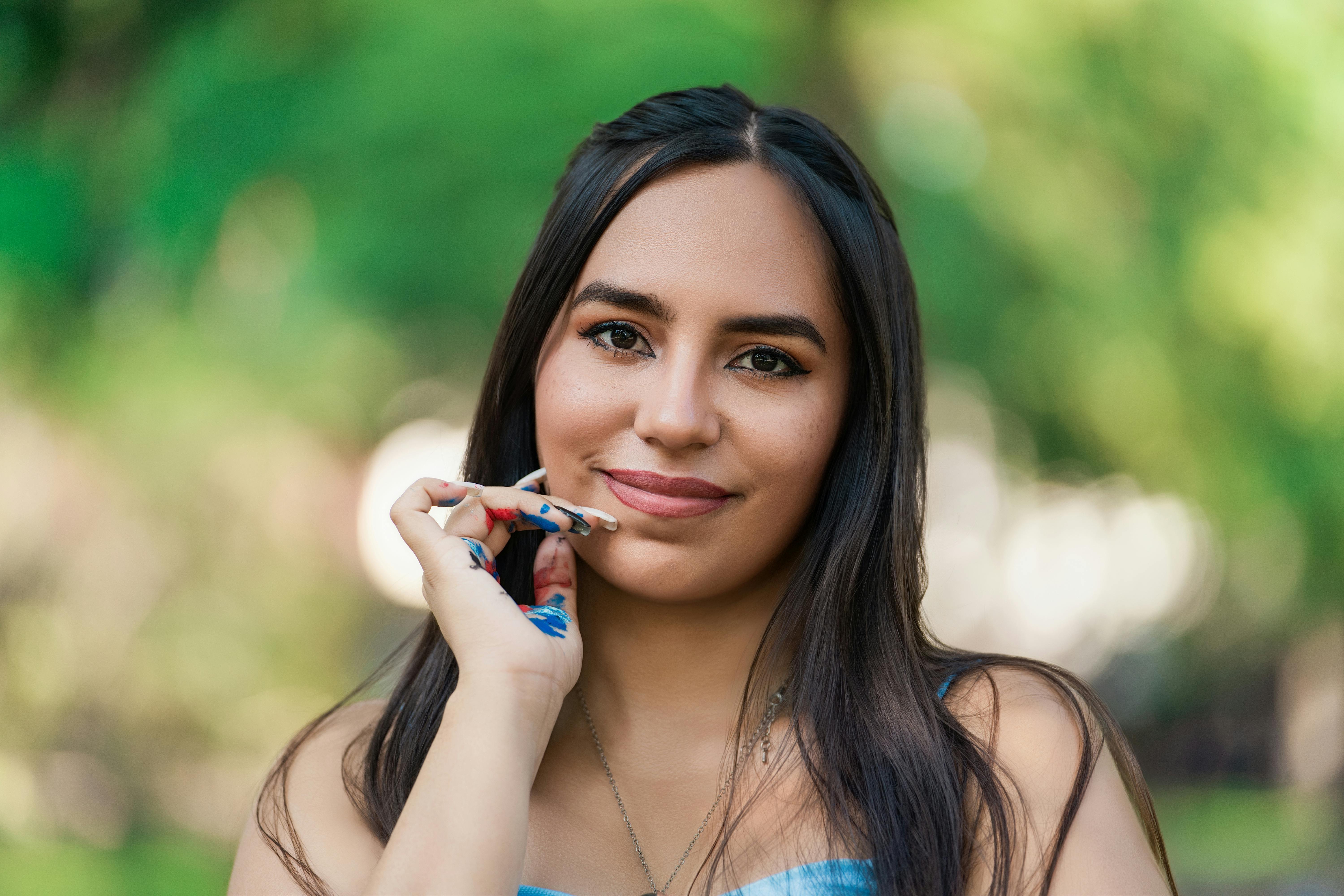 Miễn phí Chân dung một phụ nữ trẻ với lớp sơn trên tay, đang mỉm cười giữa khung cảnh thiên nhiên ngoài trời. Ảnh lưu trữ