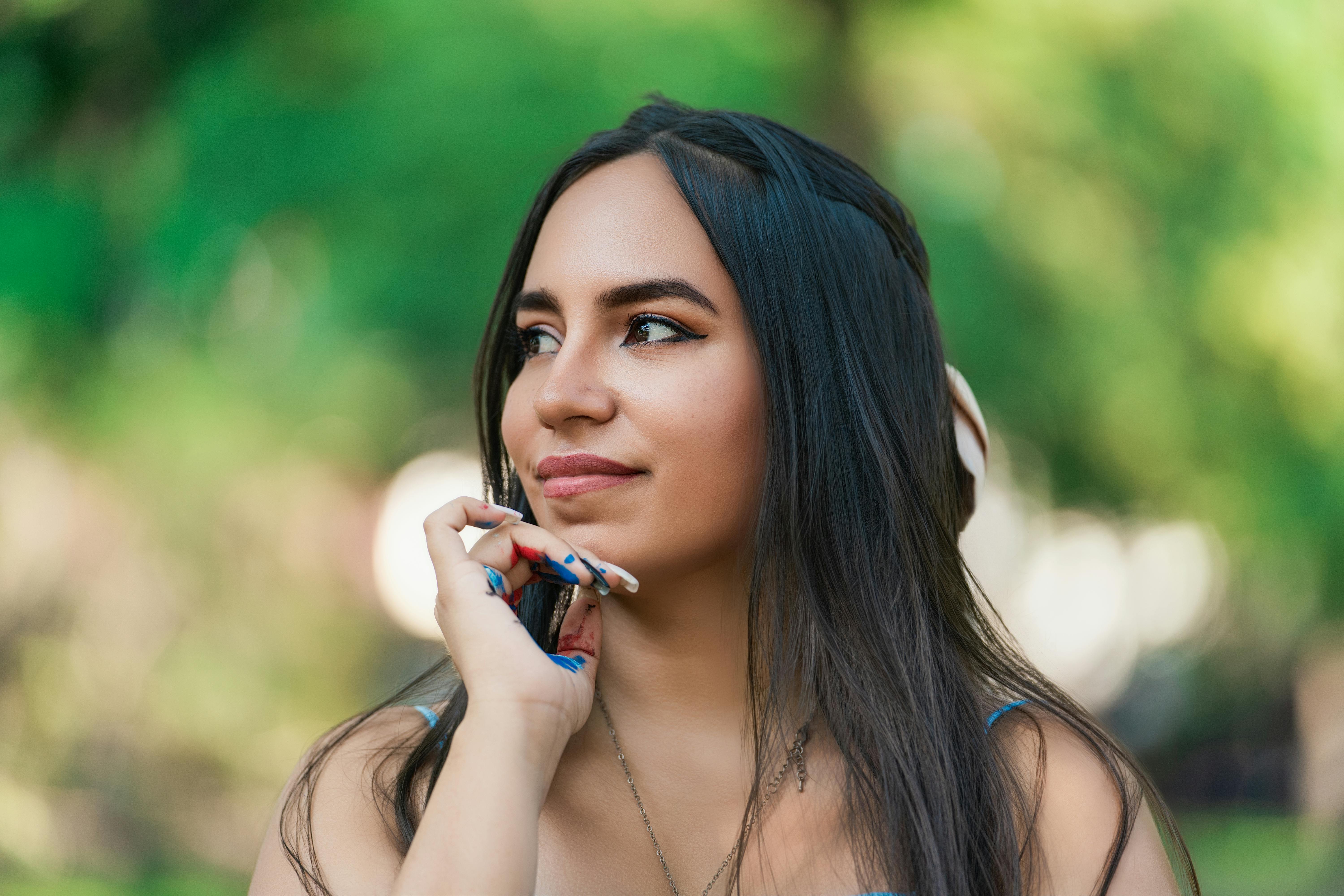 Free Portrait of a woman enjoying a sunny day outdoors, captured in a thoughtful pose. Stock Photo