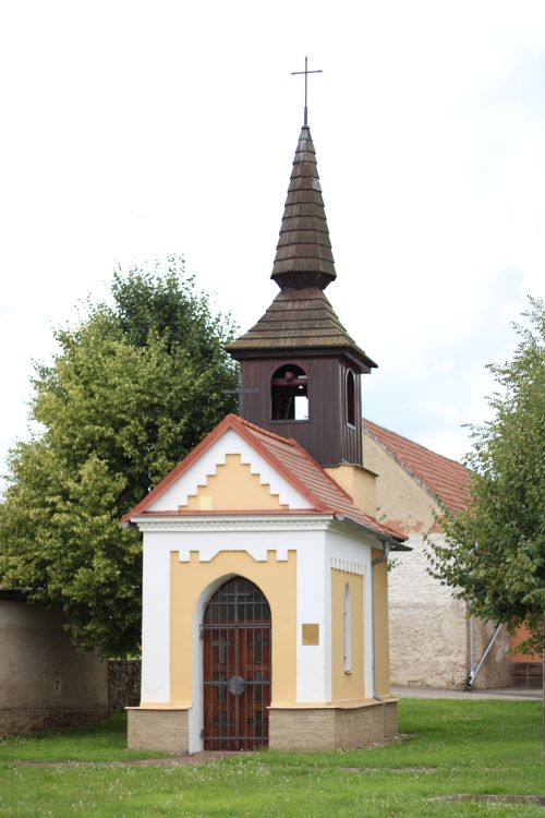 Free A quaint chapel with a wooden steeple, set amidst lush greenery in a rural area. Stock Photo