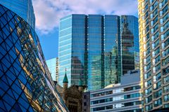 A vibrant cityscape featuring modern skyscrapers reflecting the blue sky and clouds.