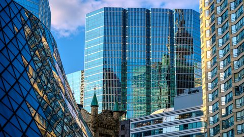 A vibrant cityscape featuring modern skyscrapers reflecting the blue sky and clouds.