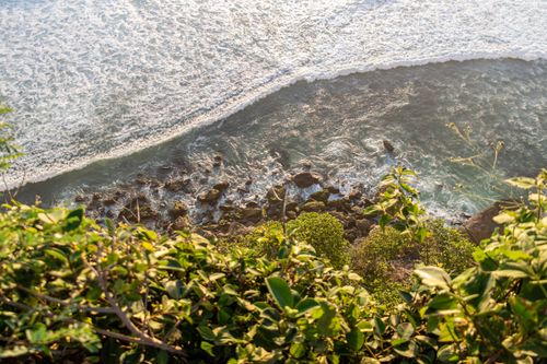 Free Aerial view of ocean waves crashing on rocks from a cliff in Bali, Indonesia. Stock Photo