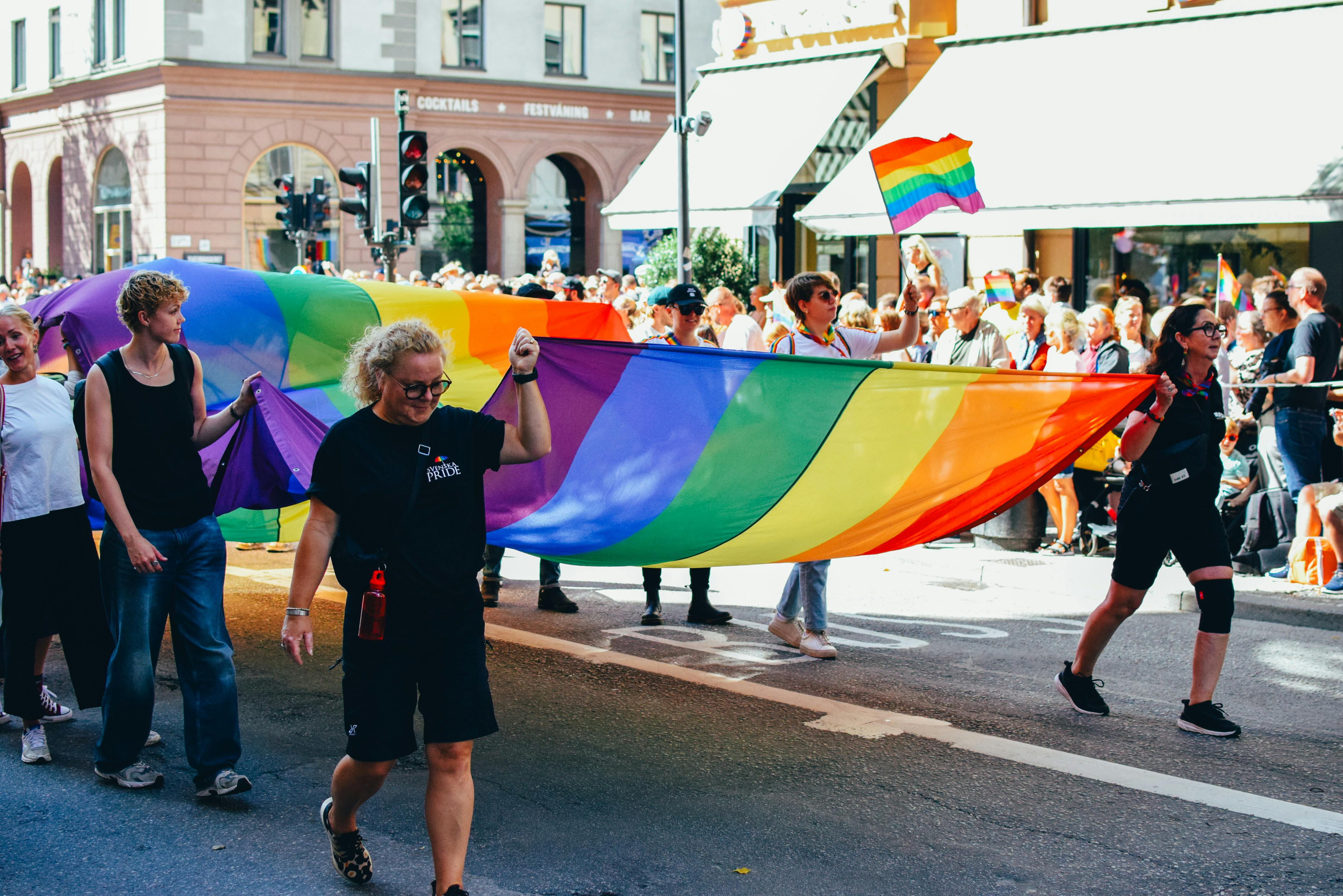 Desfile con gran bandera arcoíris en la calle