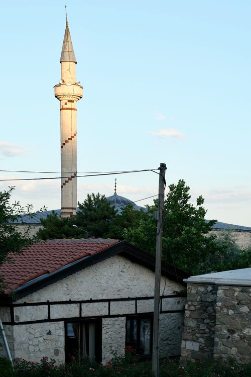 Free Traditional stone house with mosque minaret at sunset, depicting cultural architecture. Stock Photo